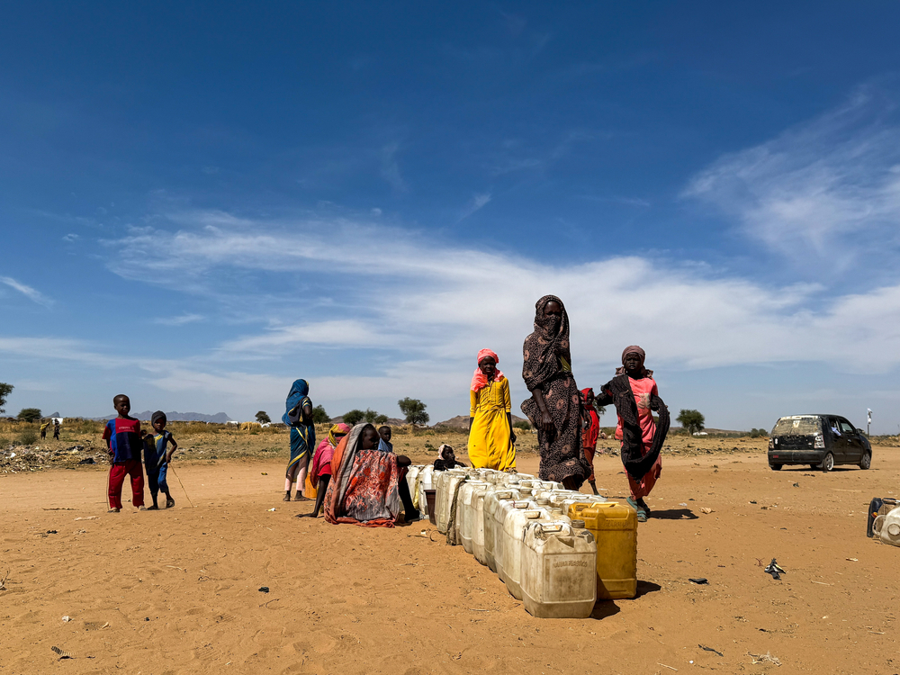 Les personnes déplacées d'El Fasher attendent leur tour avec des jerricans pour aller chercher de l'eau une fois les camions arrivés.